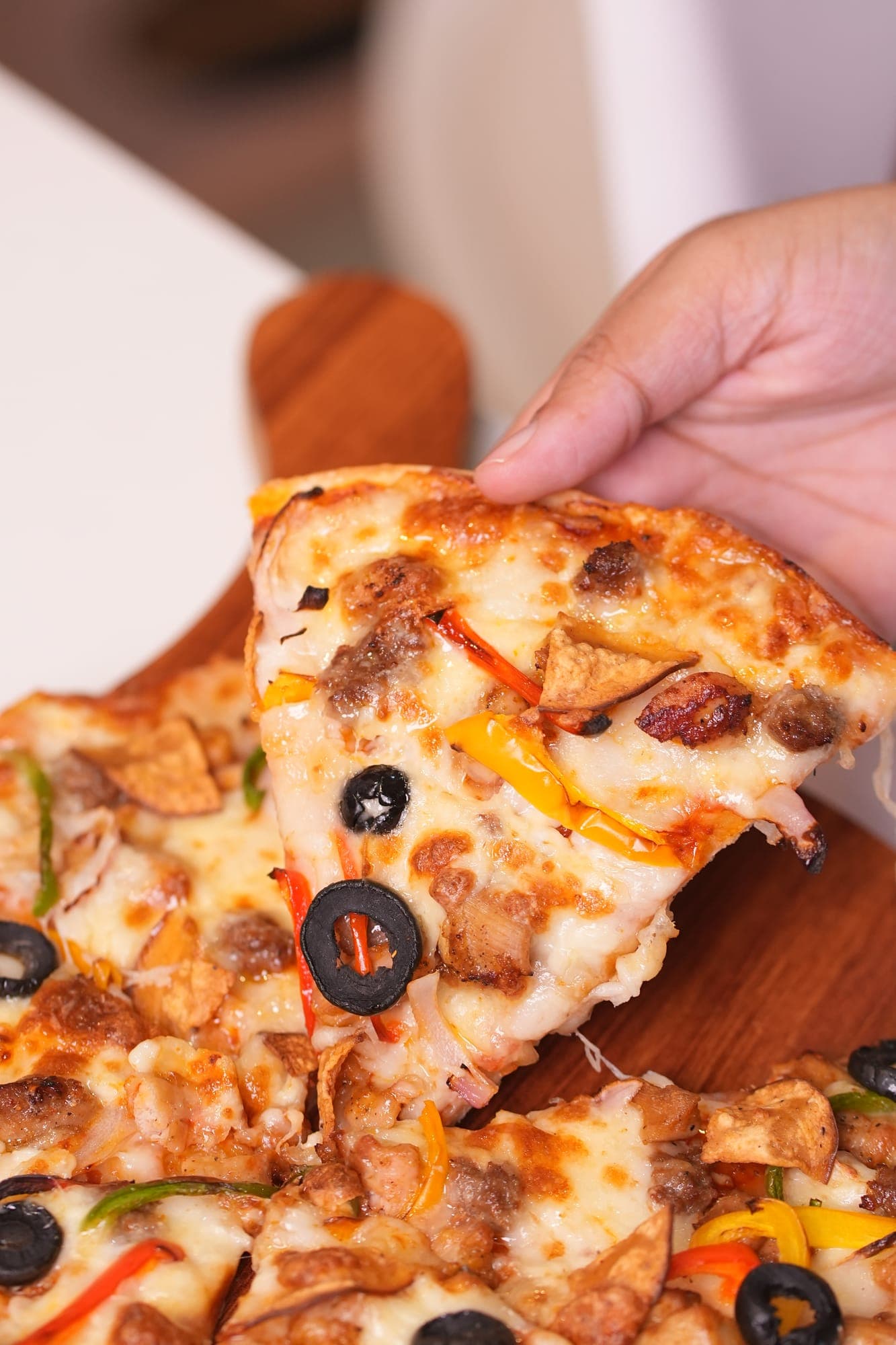 Cheesy pizza slice being pulled apart with a 1.5 litre drink bottle