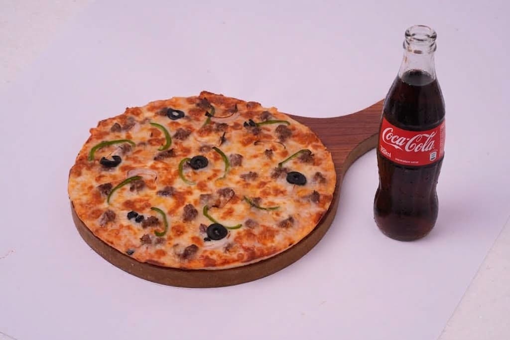 A small personal pizza with a bottled drink
