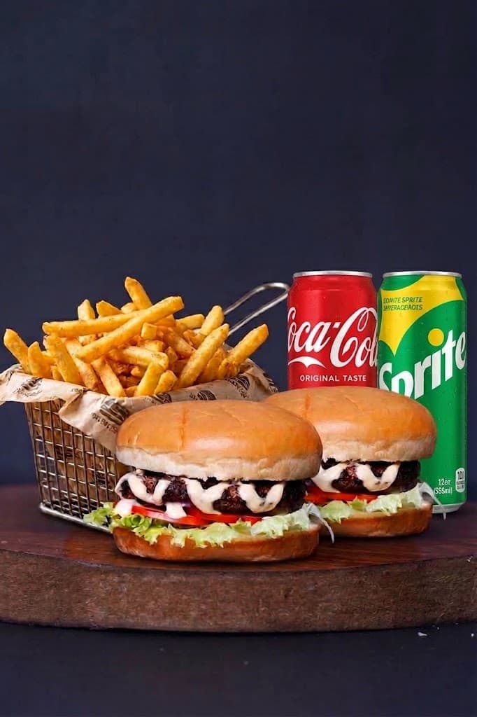 Two burgers with a basket of fries and two bottled drinks